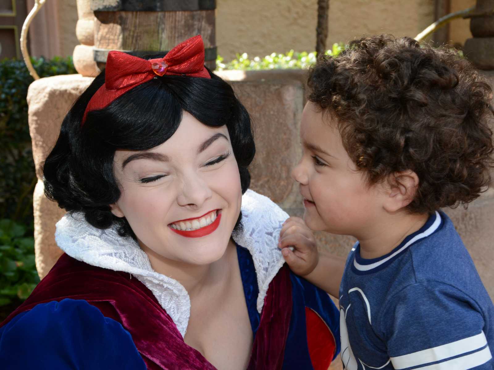 Snow White smiles while toddler stands close to her face at Disney World