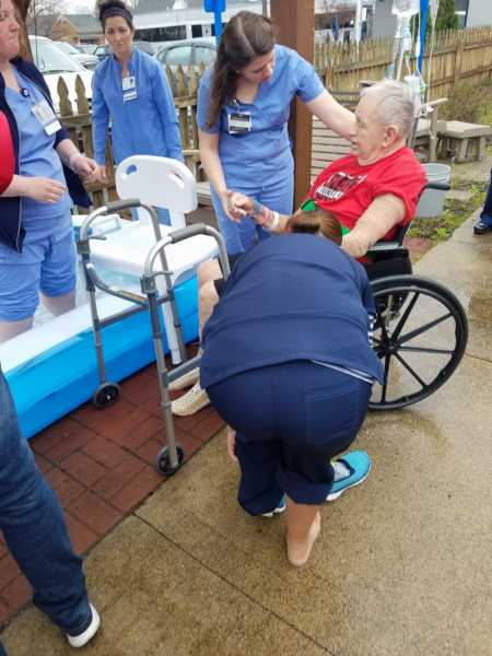 Man who had stroke sitting in wheelchair with rehab nurses