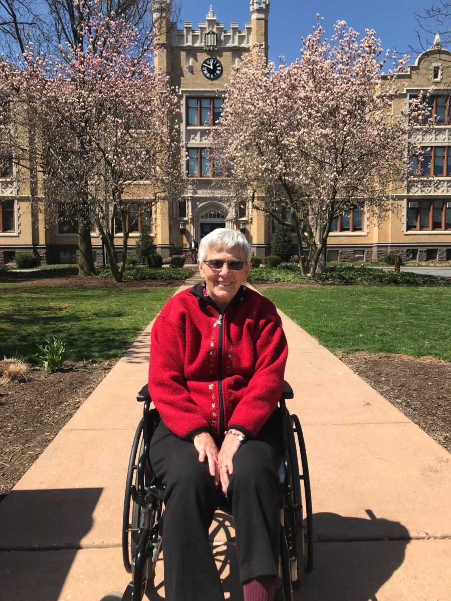 Woman with dementia sitting and smiling in wheel chair on college campus