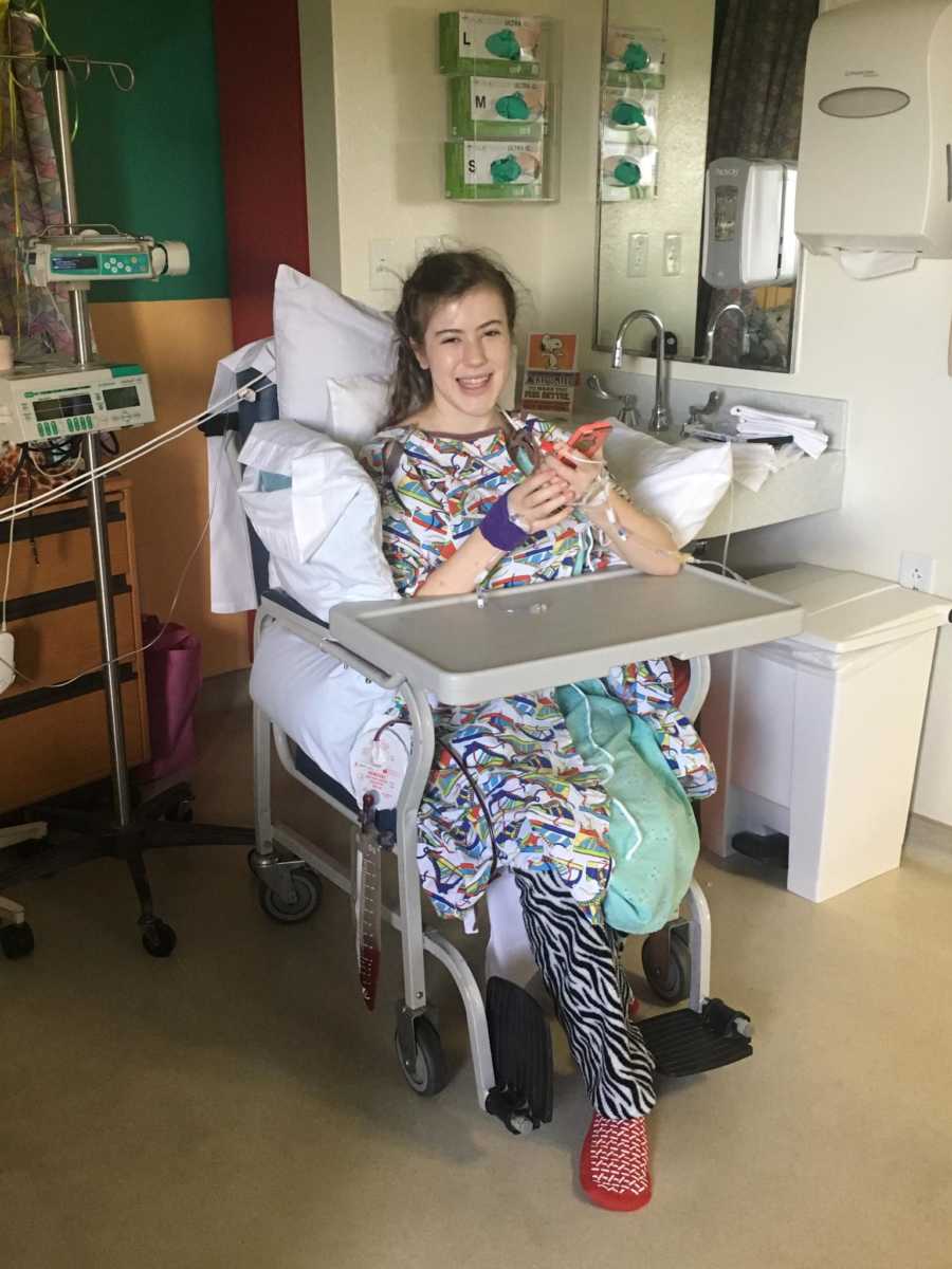 Teen girl with special needs sitting in chair in hospital smiling after spinal surgery