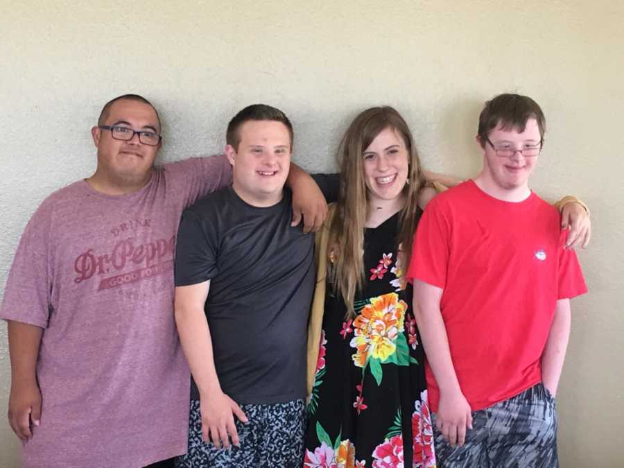 Three boy teens and girl with special needs smile arm in arm