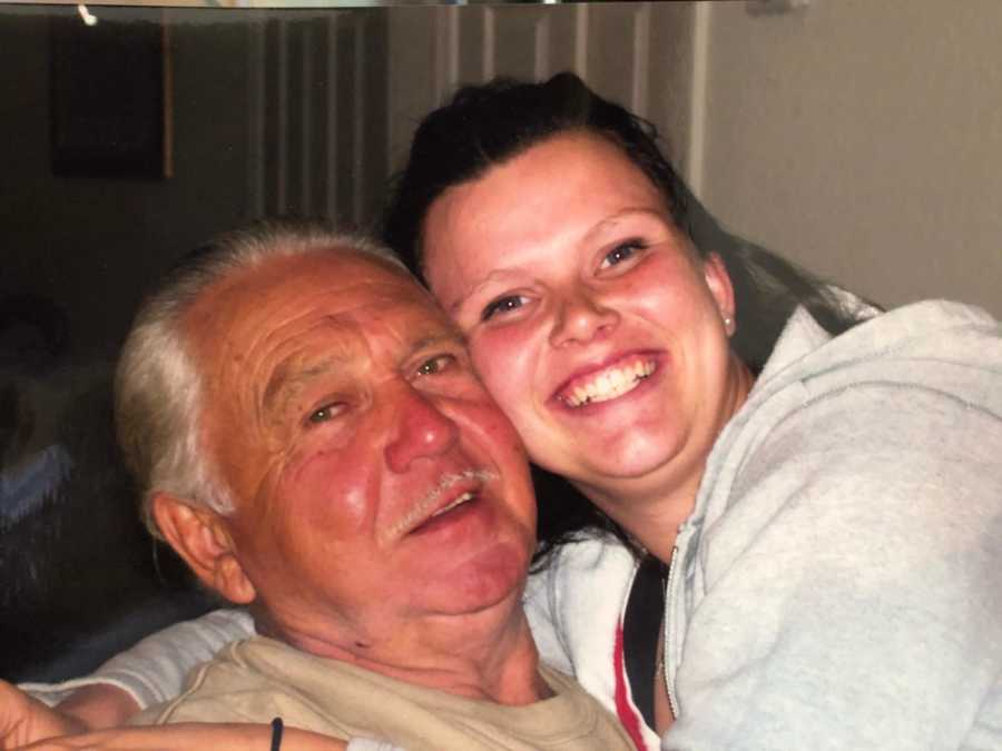 Grandfather smiling with granddaughter he helped raise sitting in his lap