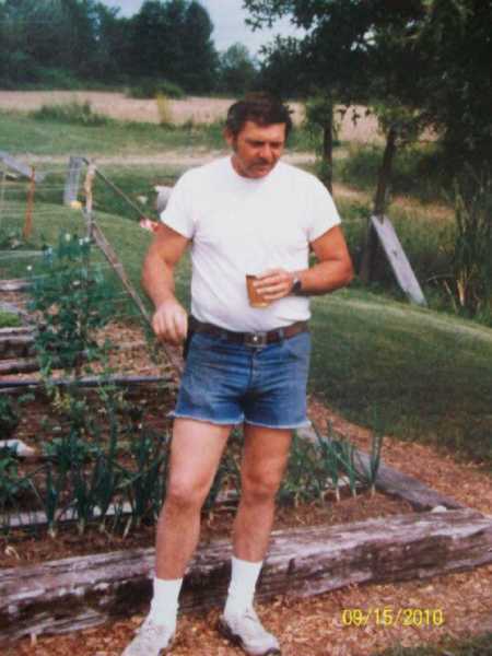 Grandfather who helped raise granddaughter standing beside vegetable garden when he was younger