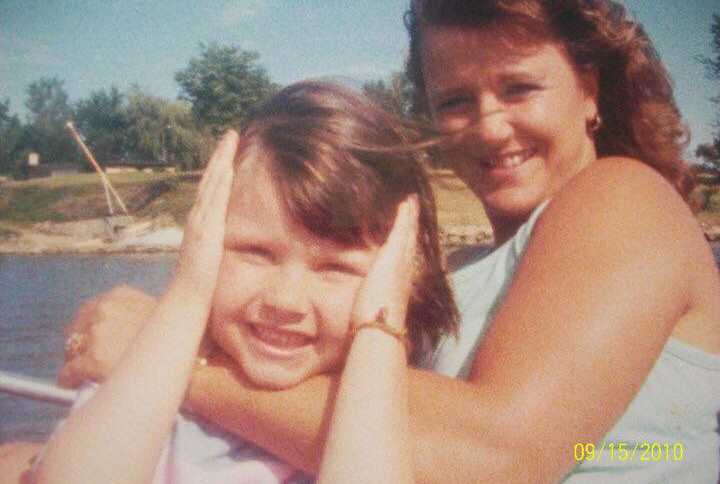 Single mother wraps arms around daughter who holds her hands up to her face on boat