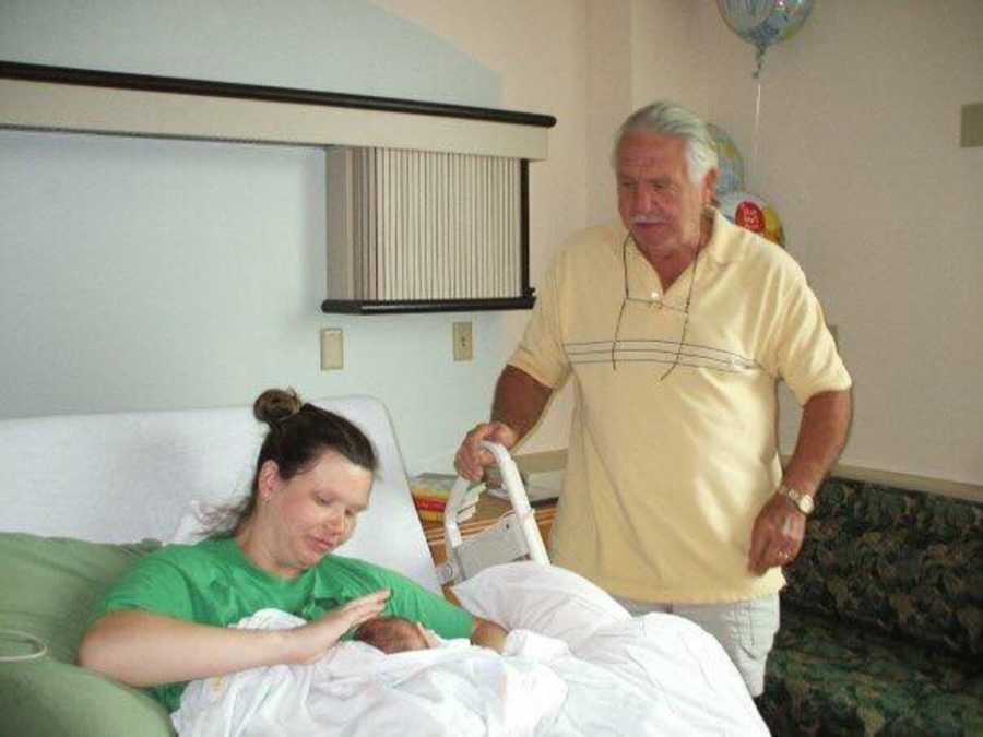 Grandfather standing over granddaughter he helped raise who just gave birth