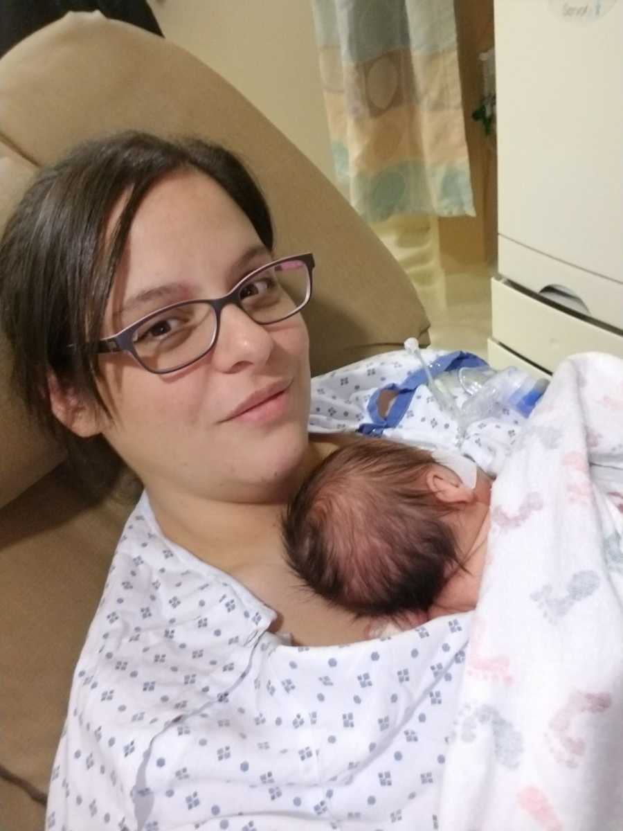 Mother who just gave birth smiles while daughter lays on her bare chest