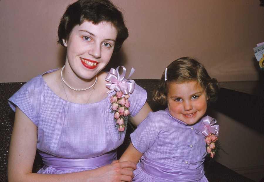 Woman smiling with daughter in purple dress she made for her