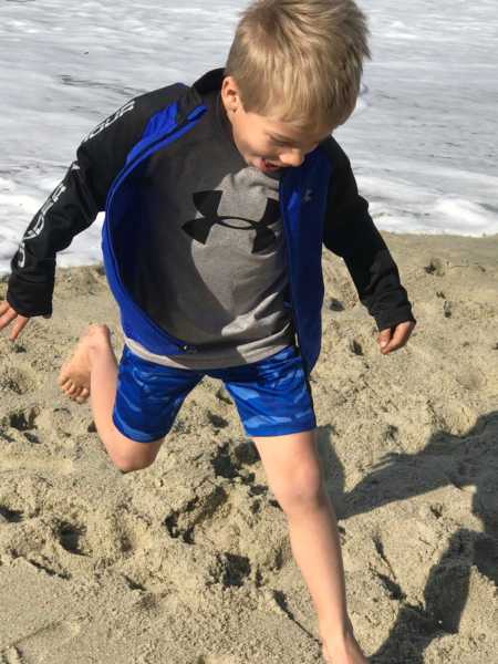 Young boy running in sand on beach