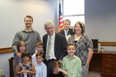 Husband and wife standing in adoption court with their 2 foster children and 4 adopted children