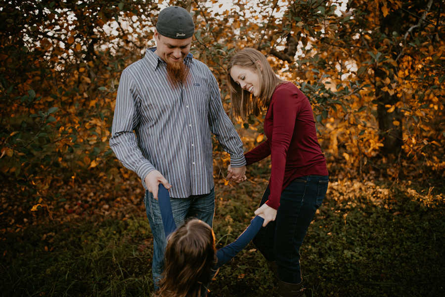 Father, mother with breast cancer and daughter all stand in circle holding hands