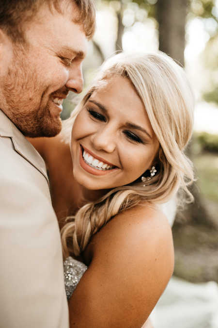 Bride and groom smile while hugging