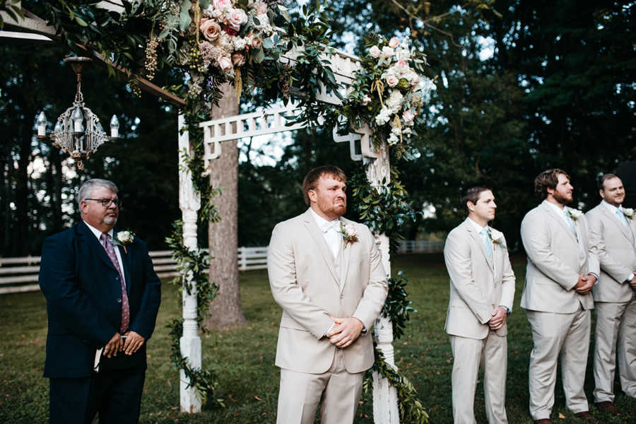 Groom choked up at altar while he looks at bride at outdoor wedding