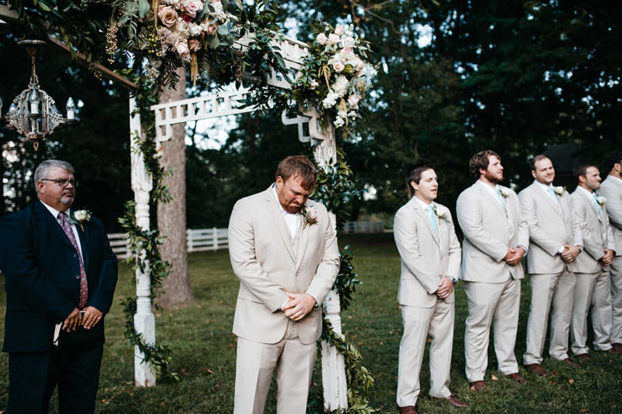 Groom looks down choked up at altar at outdoor wedding