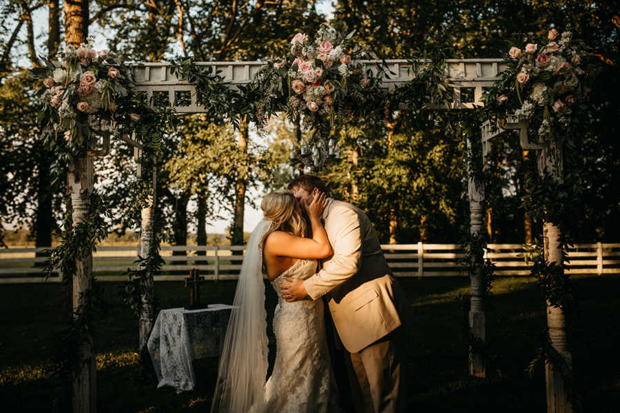 Bride and groom share kiss at altar of outdoor wedding