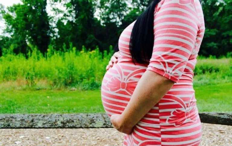 Close of of woman holding her stomach who is pregnant through sperm donor