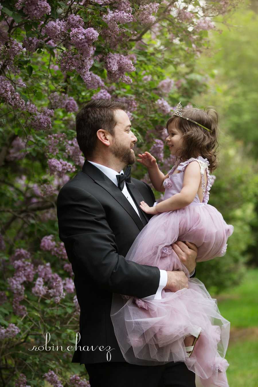 Groom holding brides daughter smiling at her