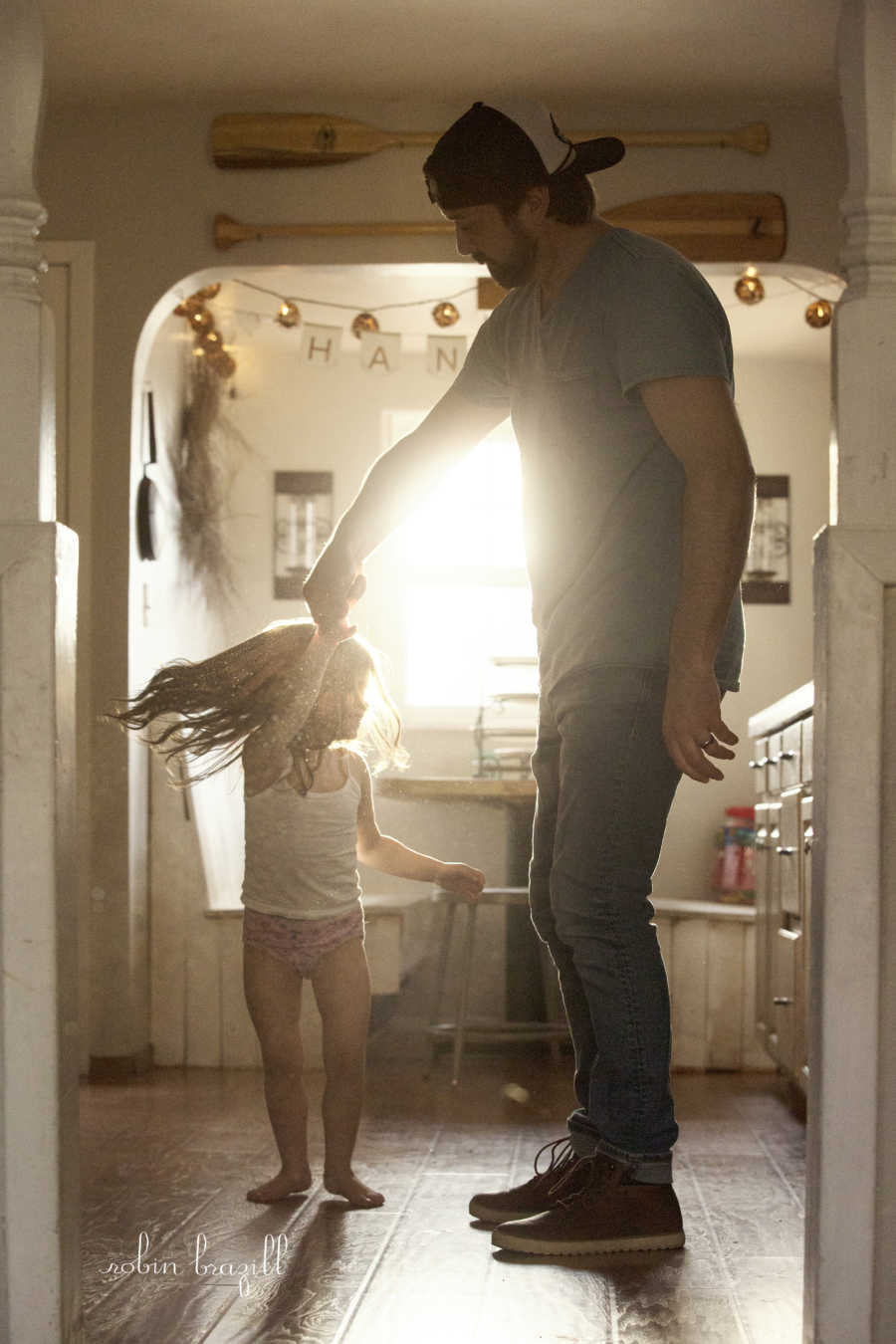 Man twirling stepdaughter in kitchen