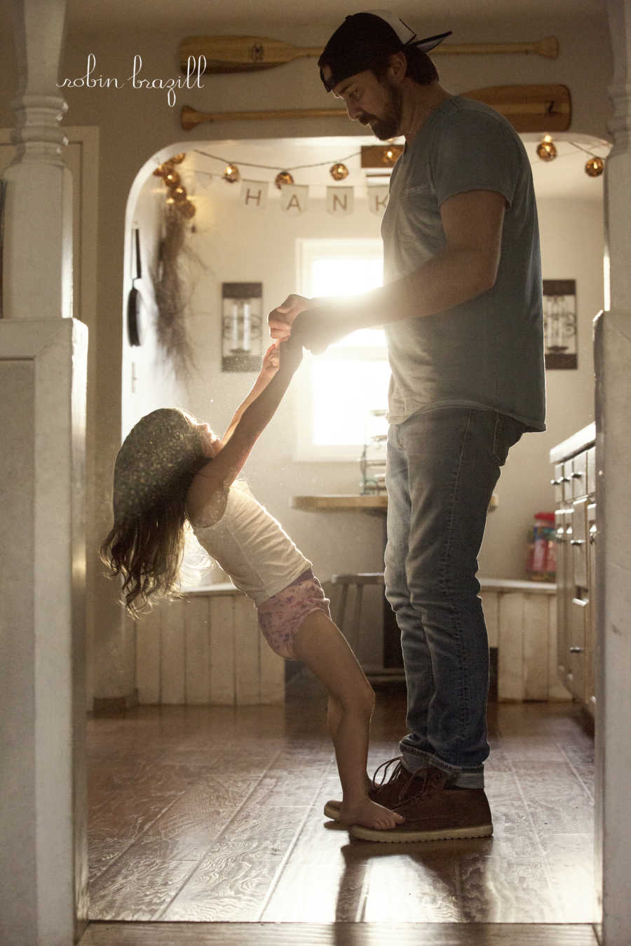 Man holding stepdaughters hands as she stands on his feet