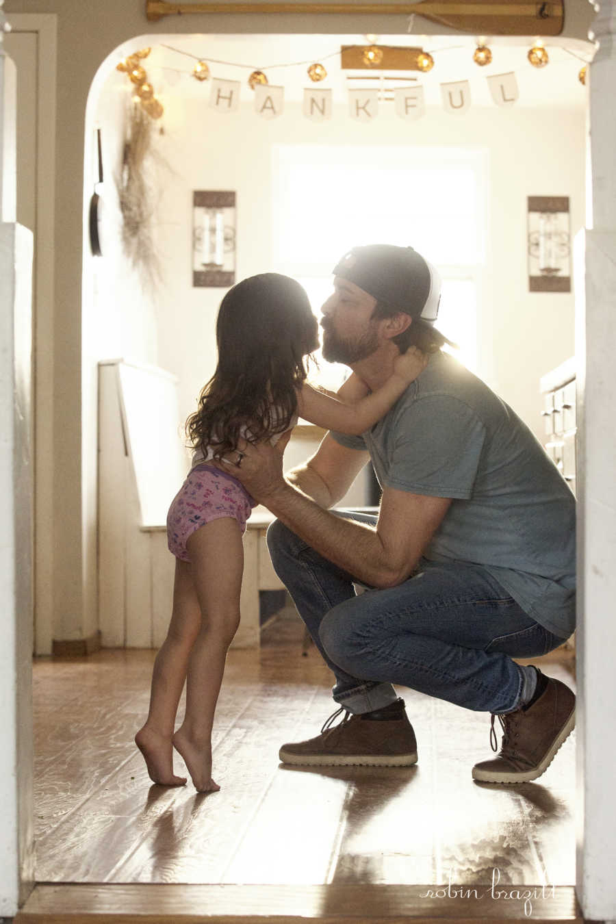 Man crouches to floor kissing stepdaughter on the lips