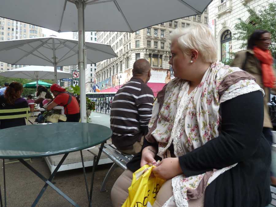 Woman sitting at table on side of street before weight loss journey