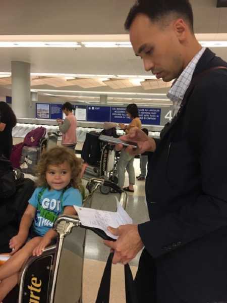 Stranger pushing toddler in cart to help mother through customs