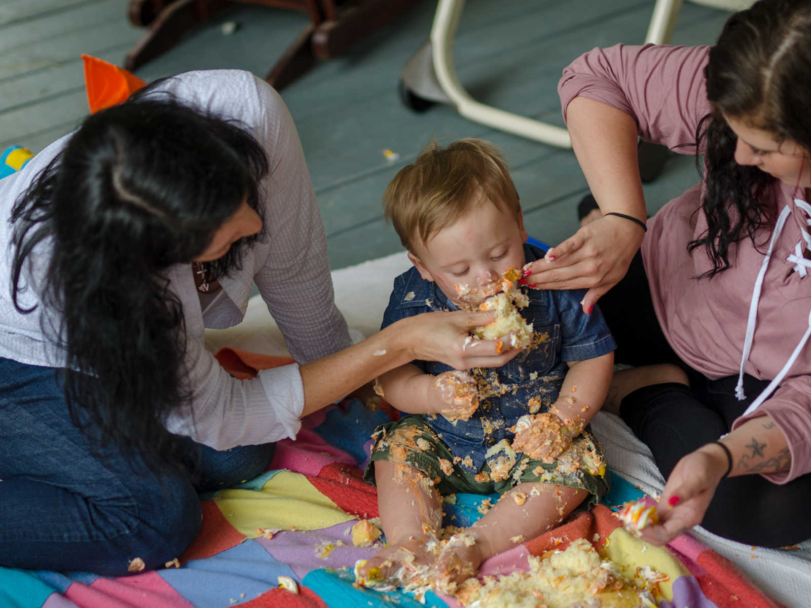 Birth mother and adopted mother stuff birthday cake into son's mouth