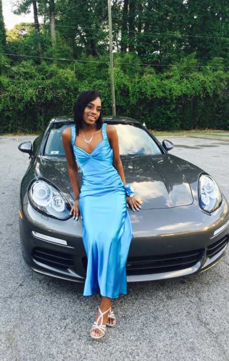 Teen dressed for prom sits on hood of porsche that is taking them to prom