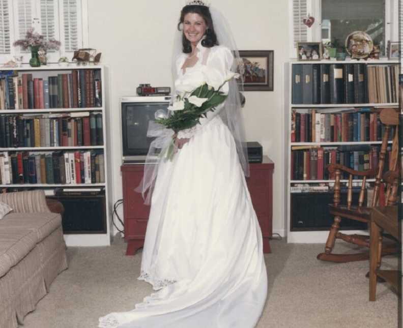 Woman standing in living room wearing wedding gown her aunt sewed for her