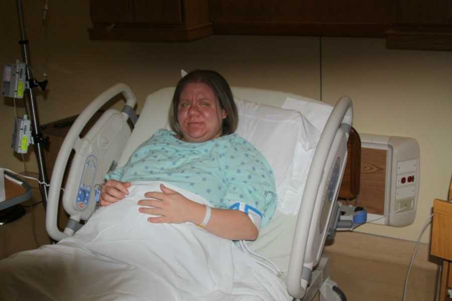 Pregnant woman who has six adopted children lays in hospital bed holding her stomach