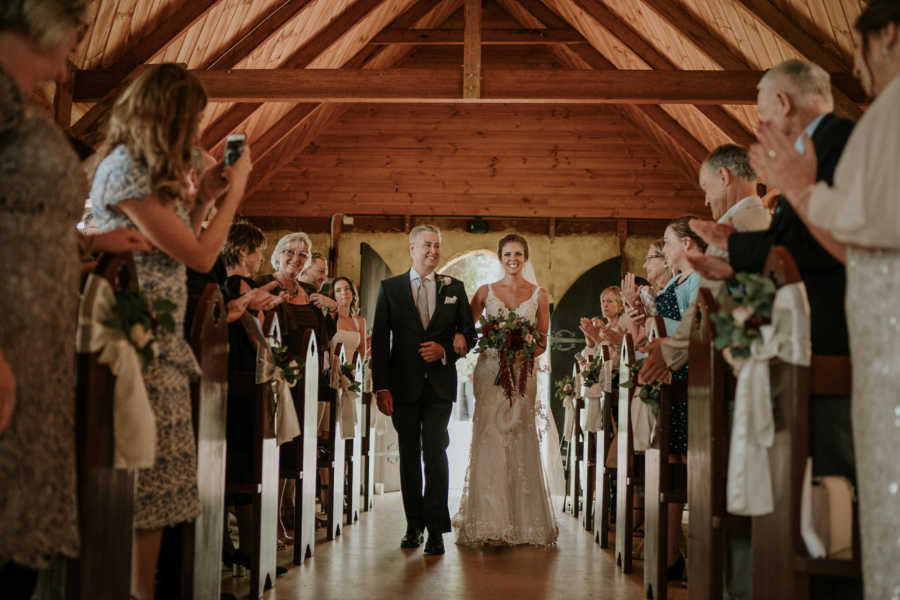 Bride of groom whose father has cancer walking down aisle with her father