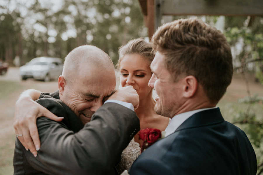 Father of groom who has cancer cries in arms of bride and son