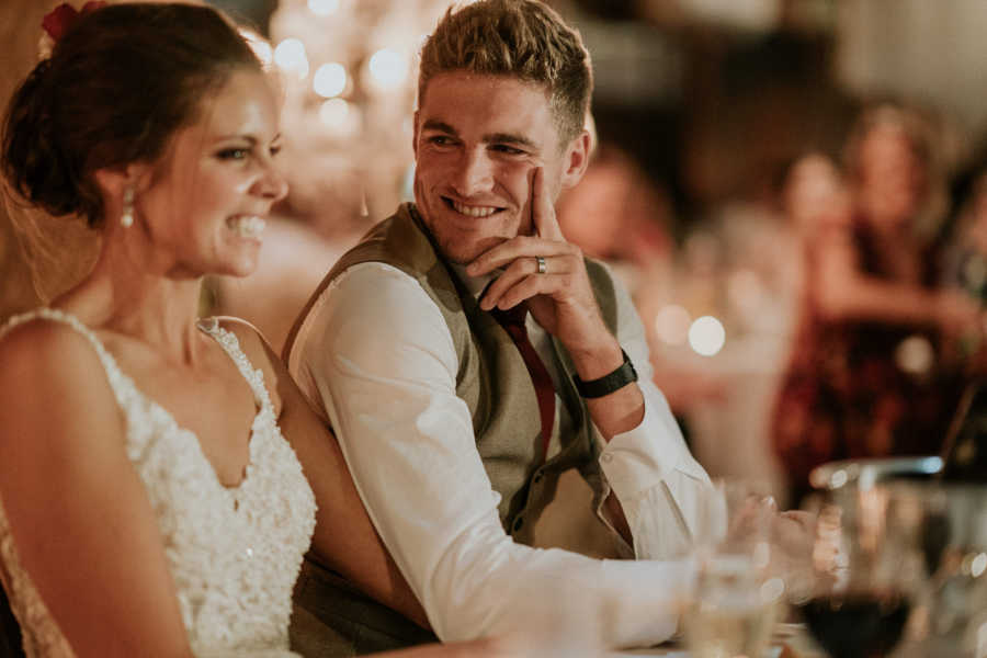 Groom whose father has cancer sits next to bride smiling at her