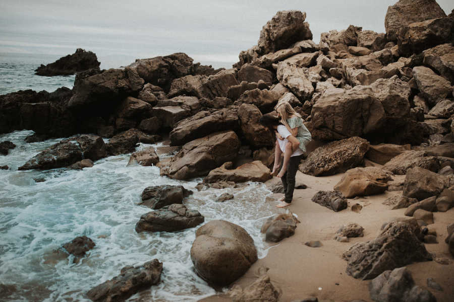 Boyfriend holds girlfriend with Spinal Muscular Atrophy on his back as he stands at ocean shore