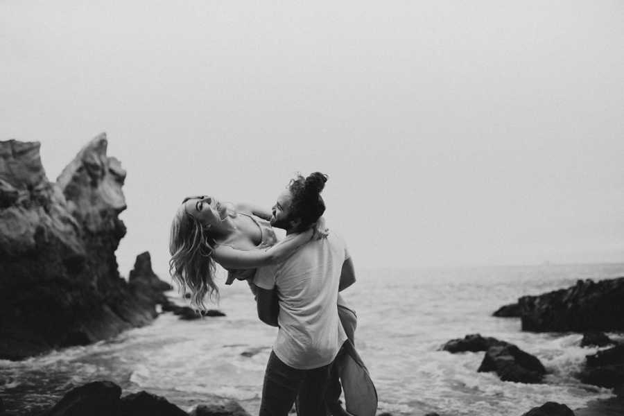 Boyfriend holding and spinning girlfriend with Spinal Muscular Atrophy on beach