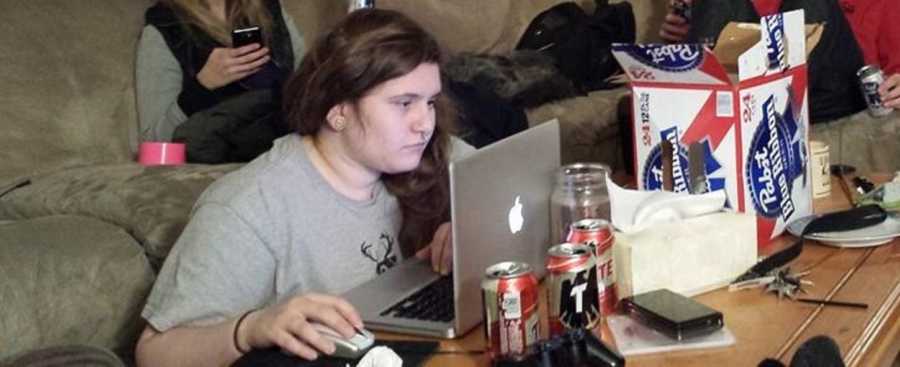 College girl sitting on floor on computer with box of beer in front of her before she loses weight