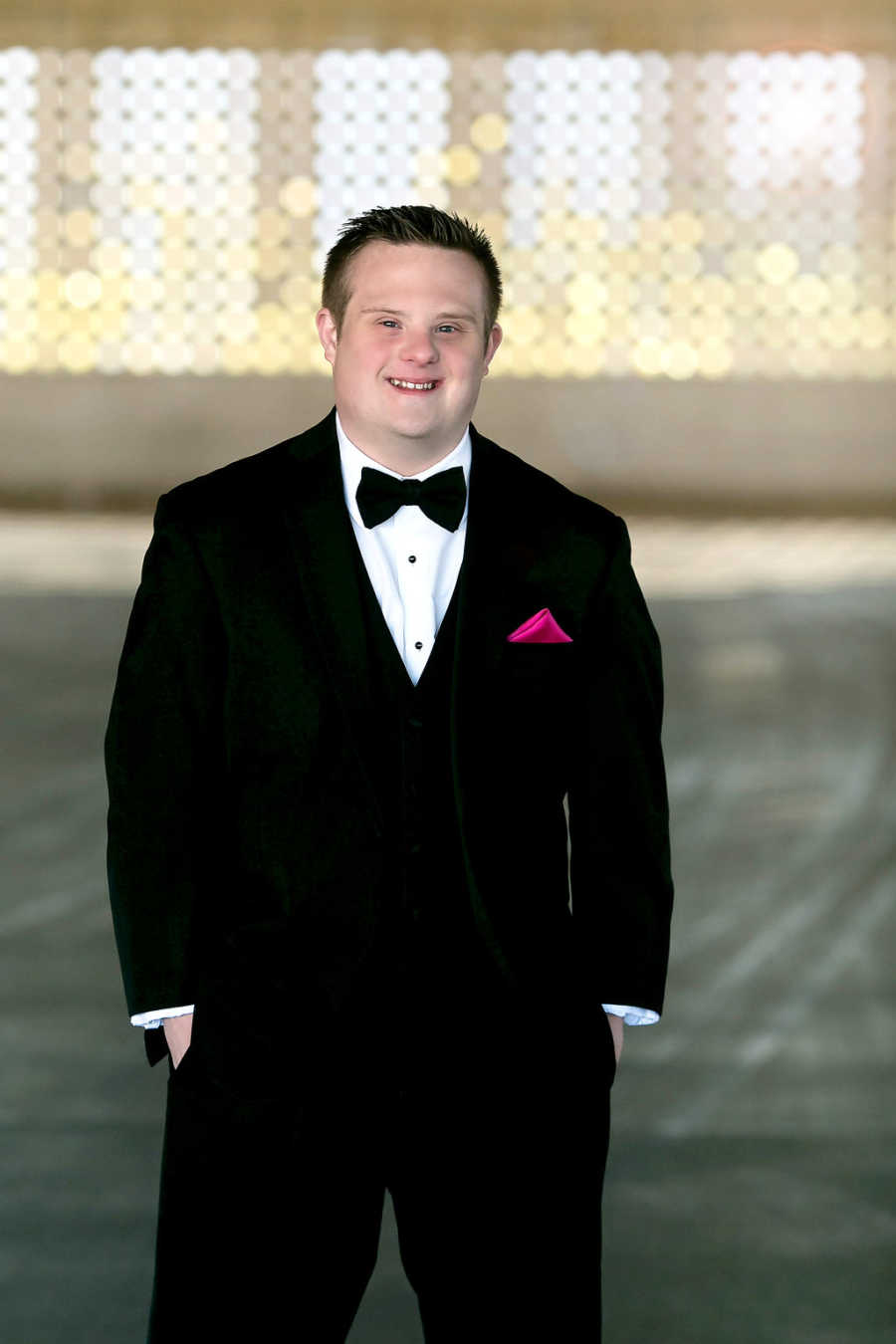 Special needs teen standing in suit smiling before prom