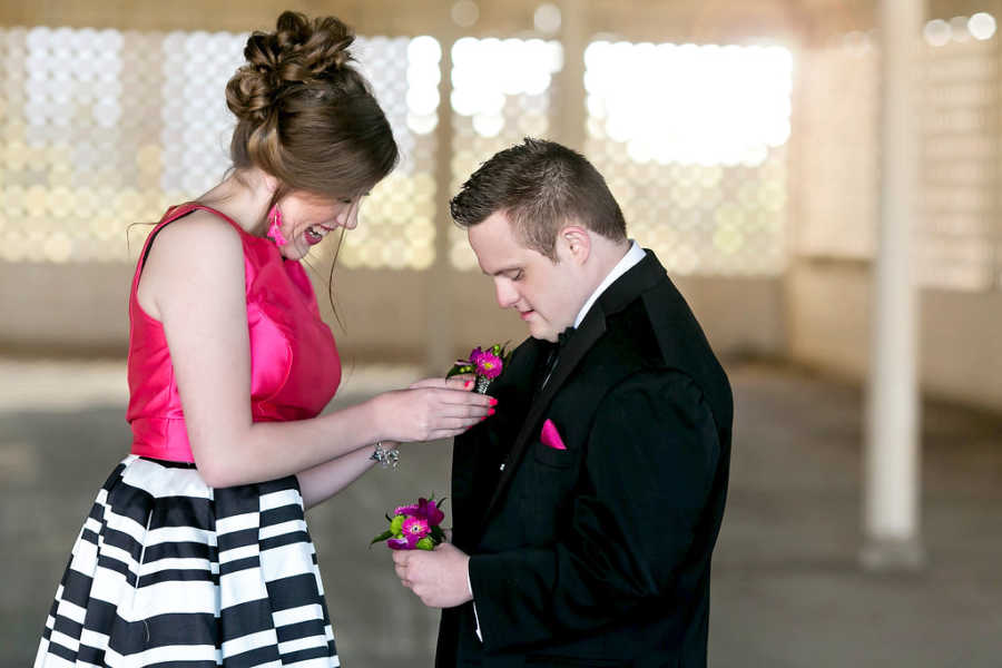 Special needs girl places boutonniere on special needs prom date