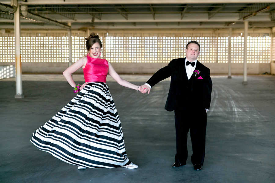 Boy and girl with special needs posing in parking lot in prom outfits