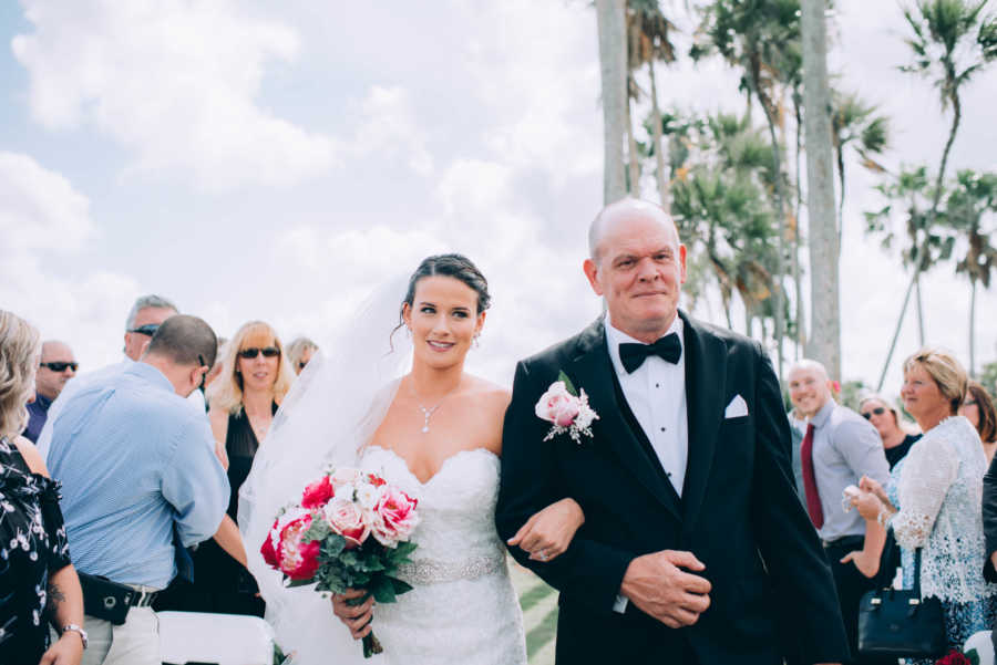 Bride walks down the aisle with father at outdoor wedding