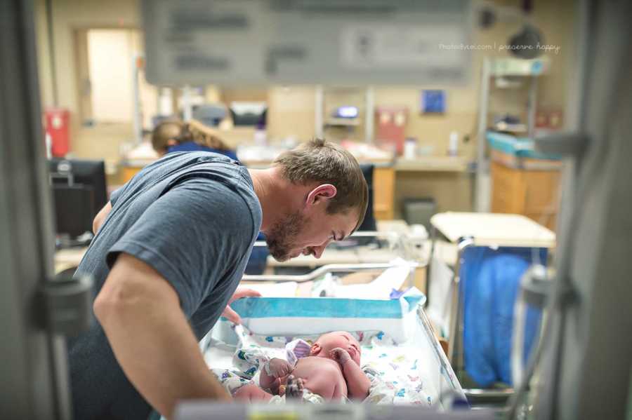 Father looking over newborn who is lying down after being delivered through c-section