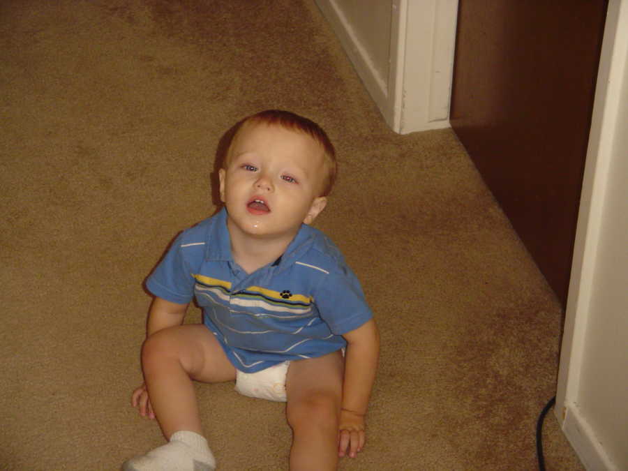 Toddler with disabilities sitting on floor in shirt and diaper