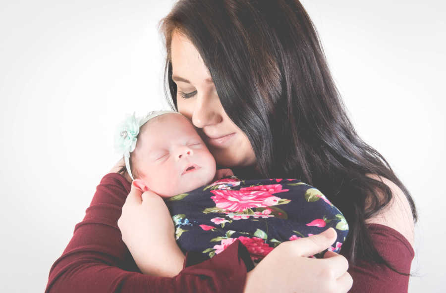 Mother holds daughter with spina bifida and Chiari malformation who is swaddled in floral blanket