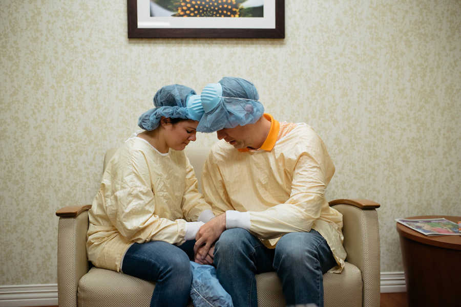 Husband and wife sit head to in waiting room waiting for their adoptive child to be born