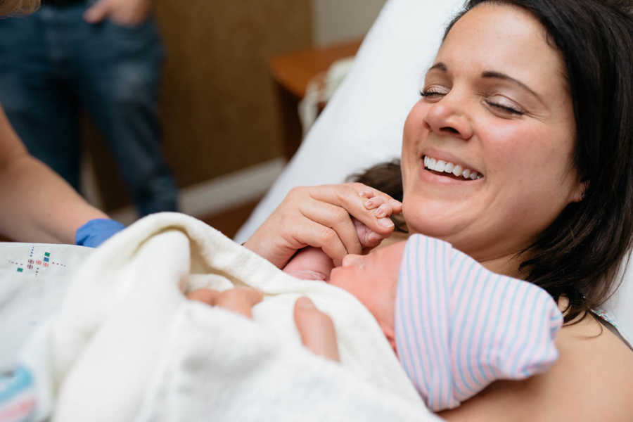 Mother smiles as she holds adopted newborn on her chest