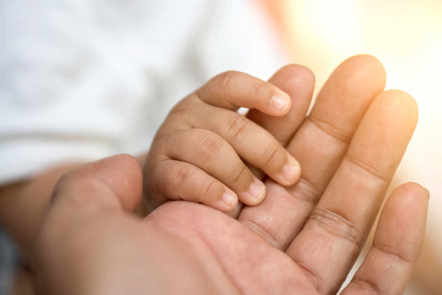 Mother who feels guilty not letting her child sleep with her's hand holding child's hand