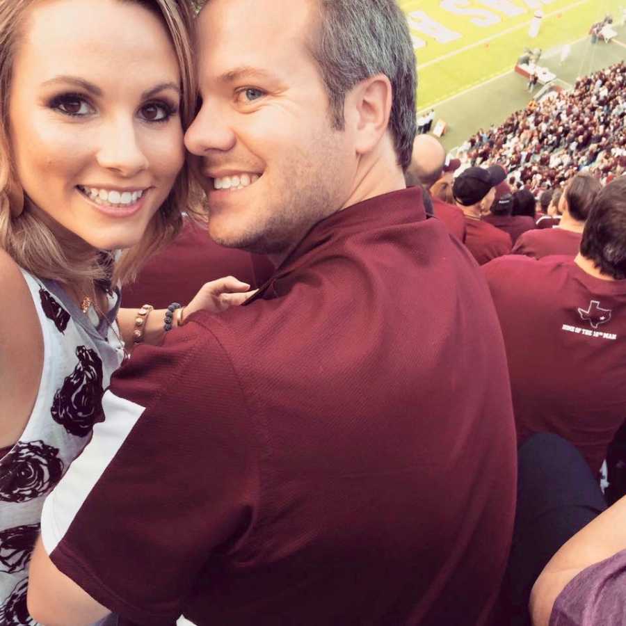 Husband and wife look back smiling in selfie in football stadium