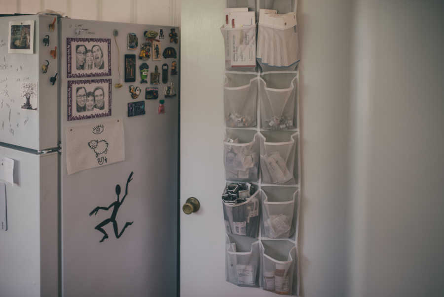 Shoe sleeve hanging on wall of kitchen holding fertility medications for infertile woman