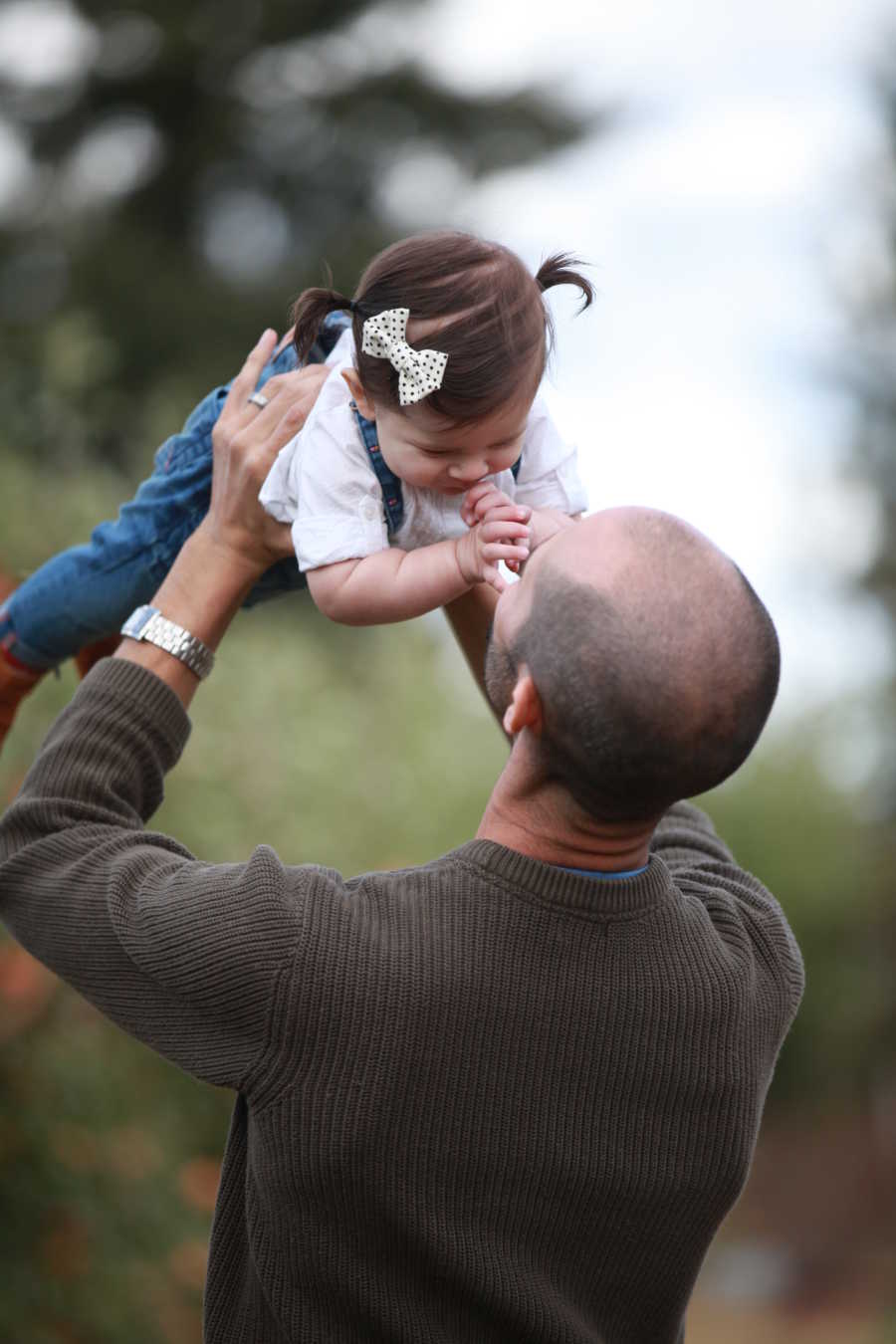 Father who has since passed holding toddler daughter in air