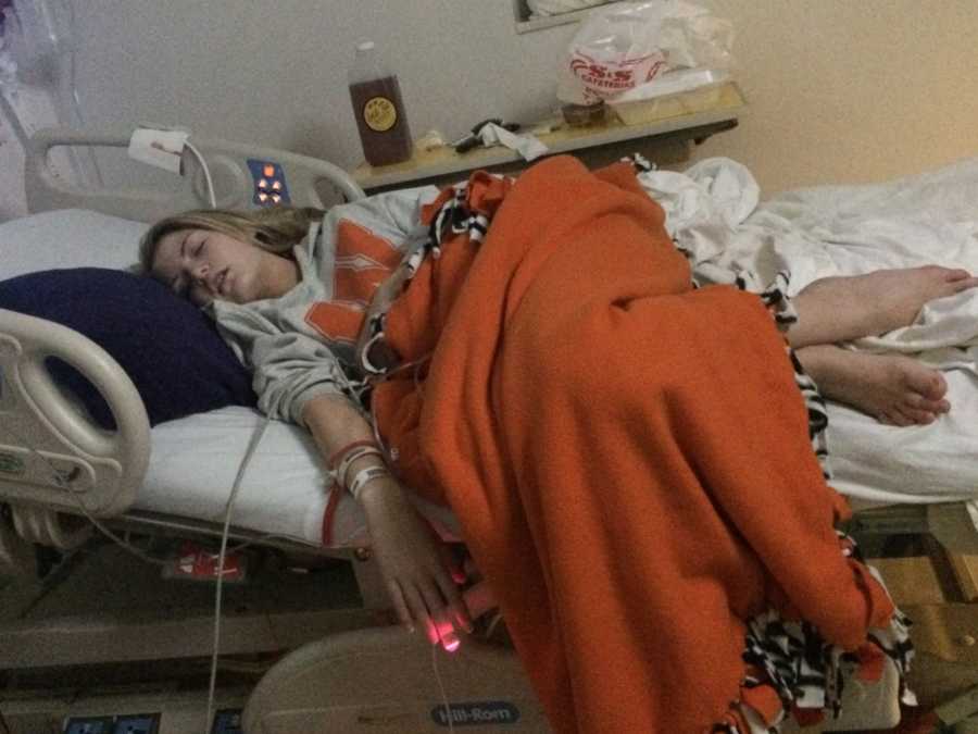 Teen with focal seizures lays asleep in hospital bed with orange blanket covering her