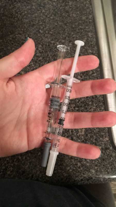 Needles of fertility medication held in woman's hand